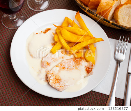 Pork chops in cream cheese sauce with french fries 128516877