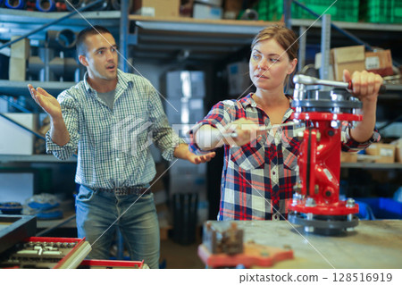 Male foreman expresses dissatisfaction with the work of a woman collecting valves in factory 128516919