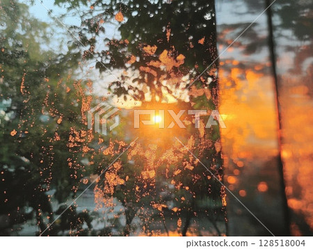 Reflection of sunset in the wet glass of a car window. 128518004
