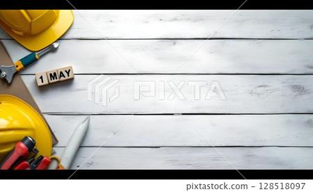 On a wooden table, construction tools and a hard hat are featured, with a background hinting at Labour Day 128518097