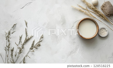 Top view of fresh milk in a wooden bowl and dry grass on white background. Top view of fresh milk in a wooden bowl and dry grass on white background. 128518225