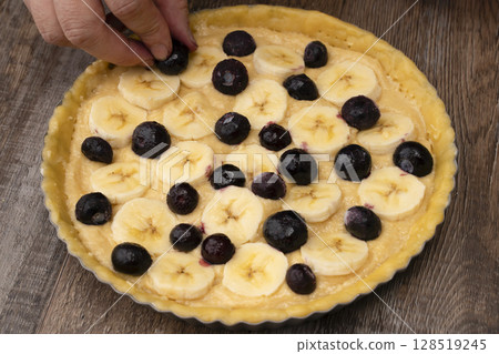 將杏仁奶油倒入塔皮中，並在上面放上香蕉和藍莓。 128519245