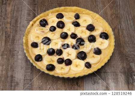 將杏仁奶油倒入塔皮中，並在上面放上香蕉和藍莓。 128519246