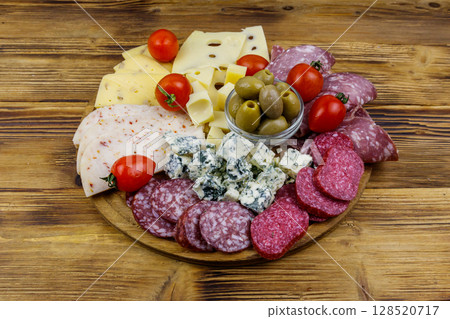 Antipasti platter with olives, cherry tomatoes, assortment of italian salami and cheese on a wooden table 128520717