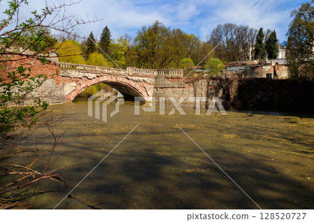 Old arched brick bridge across a pond in Sharovka Palace park in in Kharkov region, Ukraine 128520727