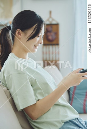 Woman playing games in the living room 128520856