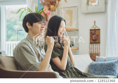 年輕的夫婦在客廳裡看電視 128522368