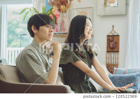 Young couple watching TV in the living room Young couple watching TV in the living room 128522369