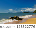 A serene scene at Trinity Beach, with crystal-clear waters of the Coral Sea, framed by lush tropical greenery, just north of Cairns in Far North Queensland, Australia 128522776