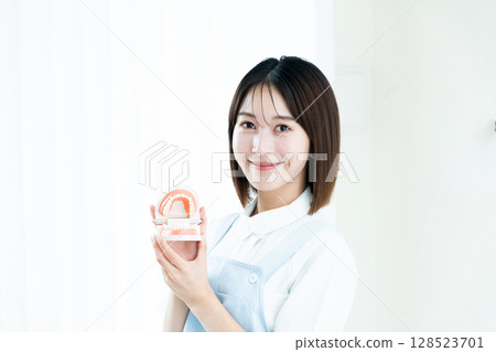 Dental staff woman holding a tooth model Dental staff woman holding a tooth model 128523701