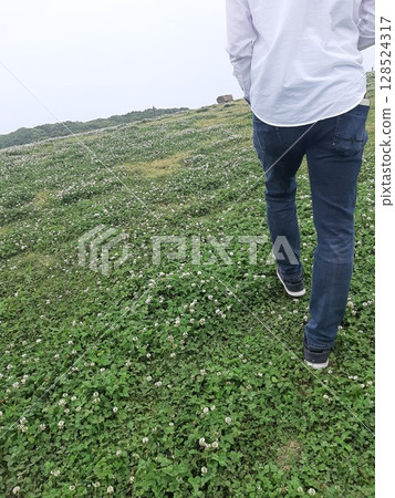 Back view of a man walking on the grass Back view of a man walking on the grass 128524317