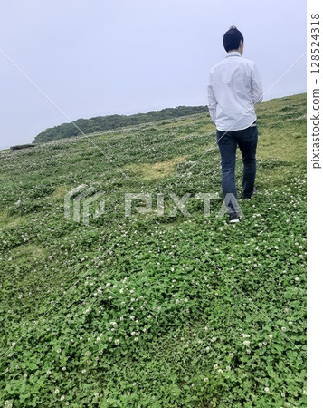 Back view of a man walking through the grass Back view of a man walking through the grass 128524318