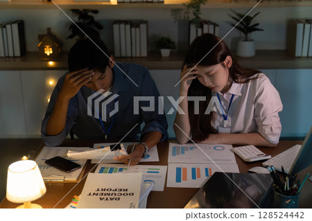 Workplace Stress. Young professionals feeling overwhelmed while analyzing project data in an office. 128524442