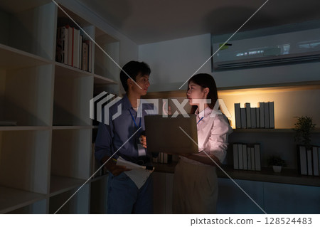 Professional Collaboration. Young colleagues discussing project details with a laptop in a modern office. Professional Collaboration. Young colleagues discussing project details with a laptop in a modern office. 128524483