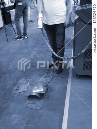 Person cleaning metal surface from rust with laser. Laser cleaning metal surfaces. Laser cleaning metal from rust. Glowing laser beam cleansing metal. Glowing beam removes removing old dirt metallic 128524710