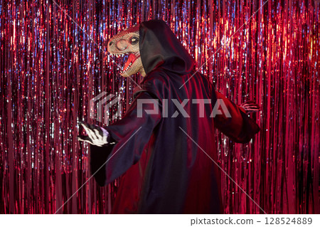 Person wearing dinosaur mask and Halloween carnival costume having fun at party. 128524889