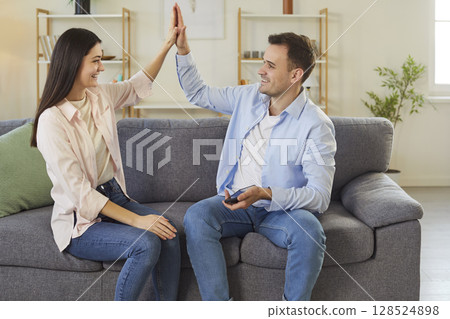Excited family happy couple moving new flat, sitting on couch at home feel excited rejoicing succeed 128524898