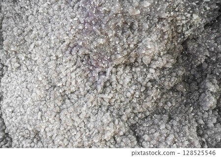 Close-up of salt or mineral crystal formation resembling a stalagmite surface with dense texture, captured inside a natural cave or underground chamber. 128525546