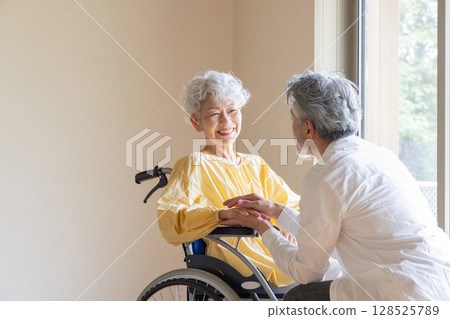 Senior man caring for a senior woman in a wheelchair Senior man caring for a senior woman in a wheelchair 128525789