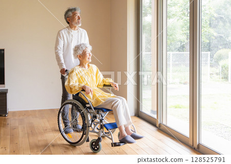 一位老人照顧一位坐輪椅的老年婦女 128525791