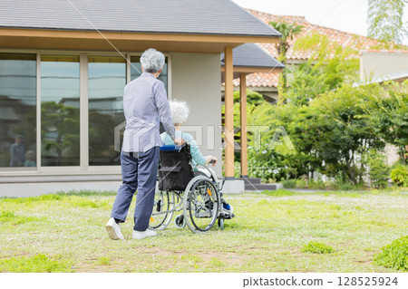 坐在輪椅上的老年夫婦在家門前行走 128525924