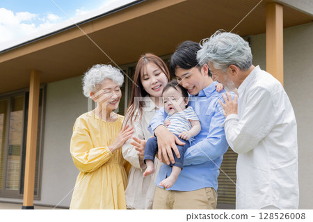 A smiling three-generation family in front of their home 128526008