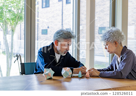 Senior men and women in wheelchairs doing origami Senior men and women in wheelchairs doing origami 128526011