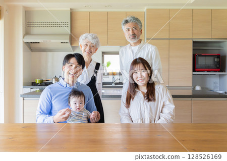 A happy photo of a three-generation family gathered around a baby in a room A happy photo of a three-generation family gathered around a baby in a room 128526169