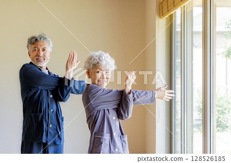 Senior couple doing flexibility exercises in pajamas 128526185
