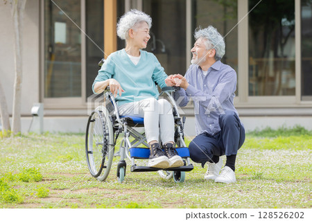 坐在輪椅上的老年夫妻在家門前聊天 128526202