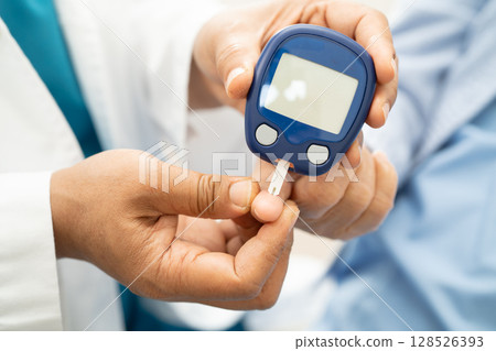 Doctor check diabetes from finger blood sugar level with finger lancet. 128526393