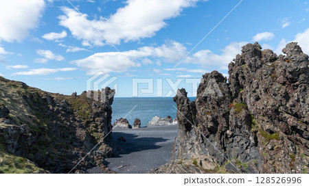 Volcanic lava rocks and rugged coastline at Djupalonssandur beach on Iceland's Snaefellsnes peninsula, within the wild and scenic Snaefellsjokull National Park. Volcanic lava rocks and rugged coastline at Djupalonssandur beach on Iceland's Snaefellsnes peninsula, within the wild and scenic Snaefellsjokull National Park. 128526996