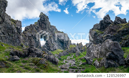 Volcanic lava formations on Djupalonssandur beach, set against the rugged coastline of Snaefellsnes peninsula in Iceland's Snaefellsjokull National Park. Volcanic lava formations on Djupalonssandur beach, set against the rugged coastline of Snaefellsnes peninsula in Iceland's Snaefellsjokull National Park. 128526997