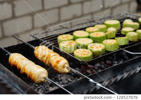 Chopped zucchini and khachapuri roasting on fire seasoned with aroma herbs and spices. Delicious fresh vegetables vegetarian grilling on barbecue smoker grid. Diet vegan bbq. Outdoor recreation Chopped zucchini and khachapuri roasting on fire seasoned with aroma herbs and spices. Delicious fresh vegetables vegetarian grilling on barbecue smoker grid. Diet vegan bbq. Outdoor recreation 128527076