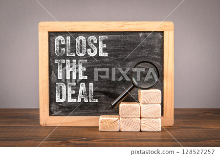 Close the Deal Motivational Message with Chalkboard, Magnifying Glass, and Wooden Blocks 128527257