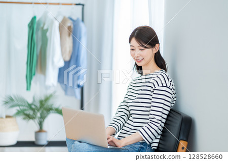 A young woman using a laptop in the living room. A young woman using a laptop in the living room. 128528660