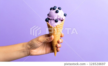 Hand holding a delicious, frozen ice cream cone, a sweet summer treat Hand holding a delicious, frozen ice cream cone, a sweet summer treat 128528697