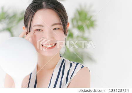 Young woman looking at a mirror 128528734