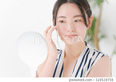Young woman looking at a mirror 128528738