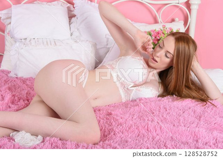 young sexy redhead in lingerie, posing on her bed in an old house 128528752