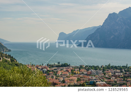 Lake Garda view with mountains and coastal Italian town under bright summer sky. High quality photo 128529565