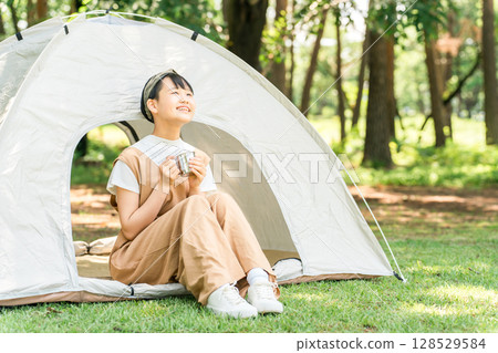 在露營地/休閒設施的帳篷前喝飲料的女孩 128529584