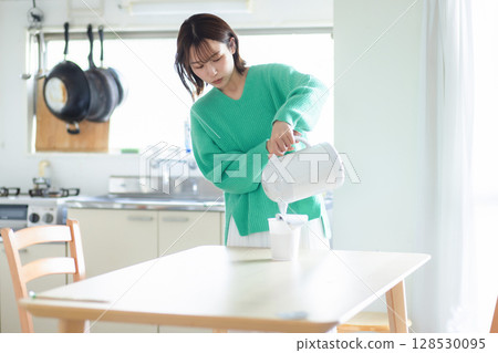 Woman pouring hot water into a pot 128530095