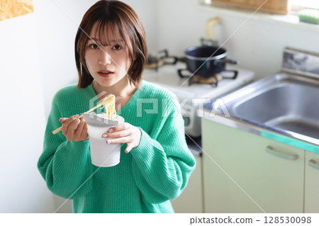 Young woman eating ramen in the kitchen 128530098