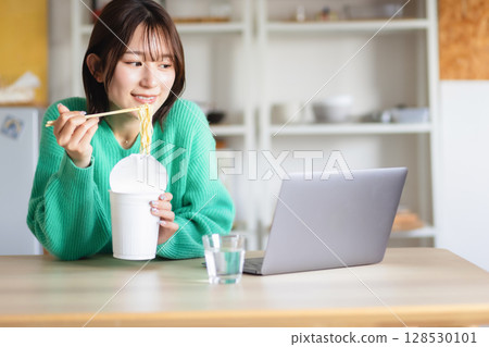 A woman eating cup ramen A woman eating cup ramen 128530101
