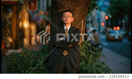 夜晚，沉思的資深商人靠在城裡的樹上 128530413
