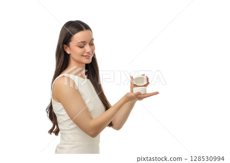 Woman happily showcases a skincare jar in her palm, isolated on white, PNG 128530994