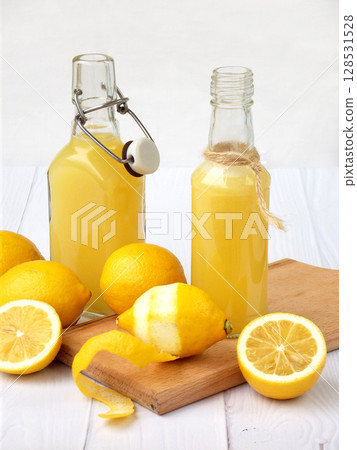 Freshly squeezed lemon juice in bottle and lemons on light background. For vitamin drink or cocktail. Selective focus. Space for text. 128531528