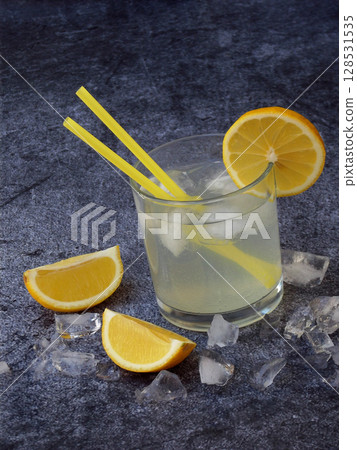 glasses of cold homemade lemonade with lemon slices, ice cubes and straws on dark background. Copy space. 128531535