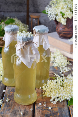 Elderflower cordial syrup and blossom flower in wooden background. Edible elderberry flowers add flavour and aroma to drink and dessert. Copy space. 128531595